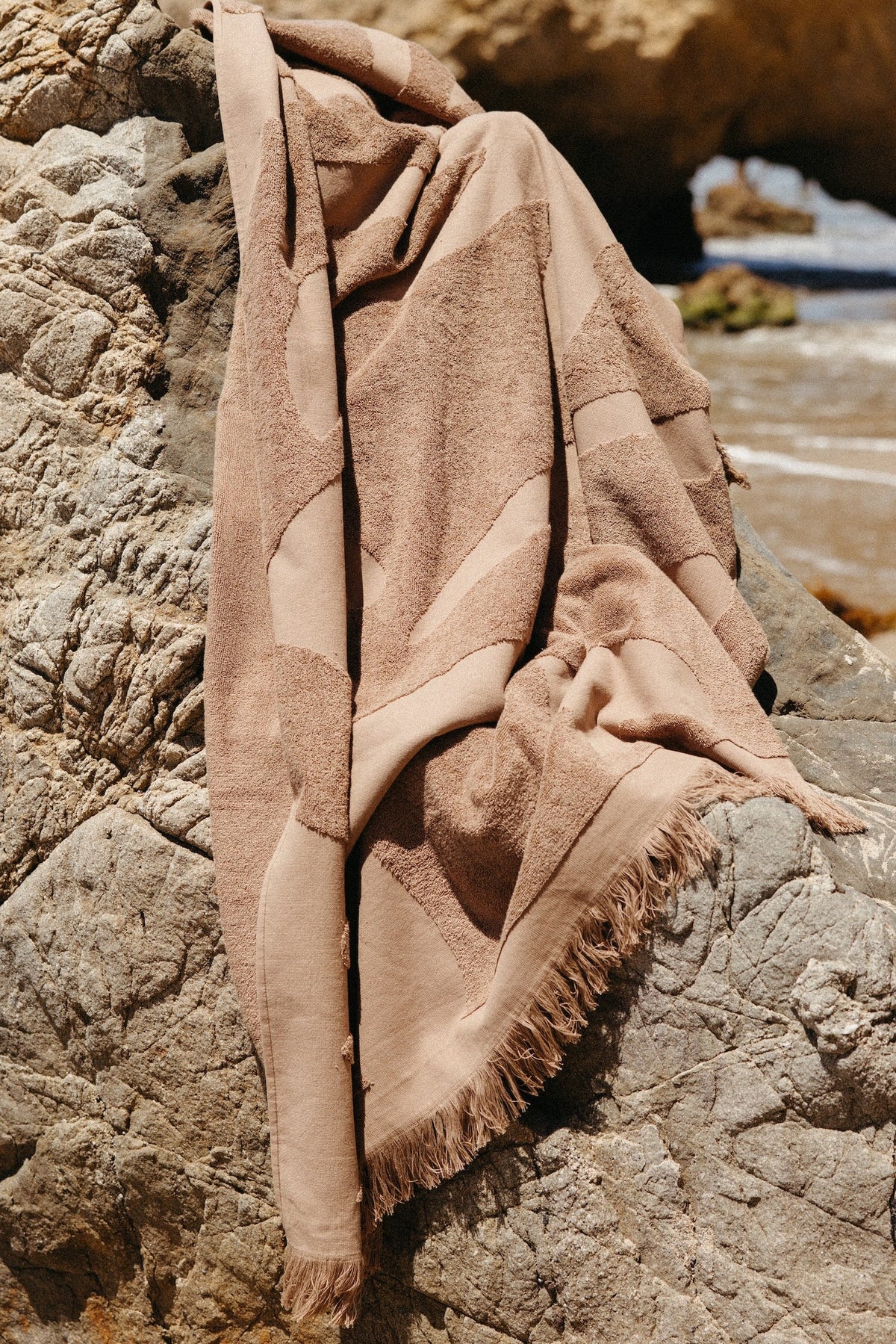 Espresso Woven Beach Towel, resting on a rock
