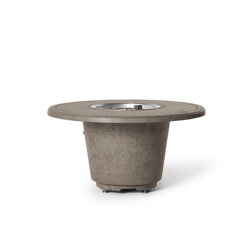 Indio Round Fire Table in Light Basalt, lit at dusk on a patio