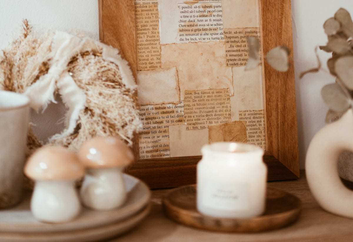 Warm-toned styled shelf with a framed collage, candle and dried stems