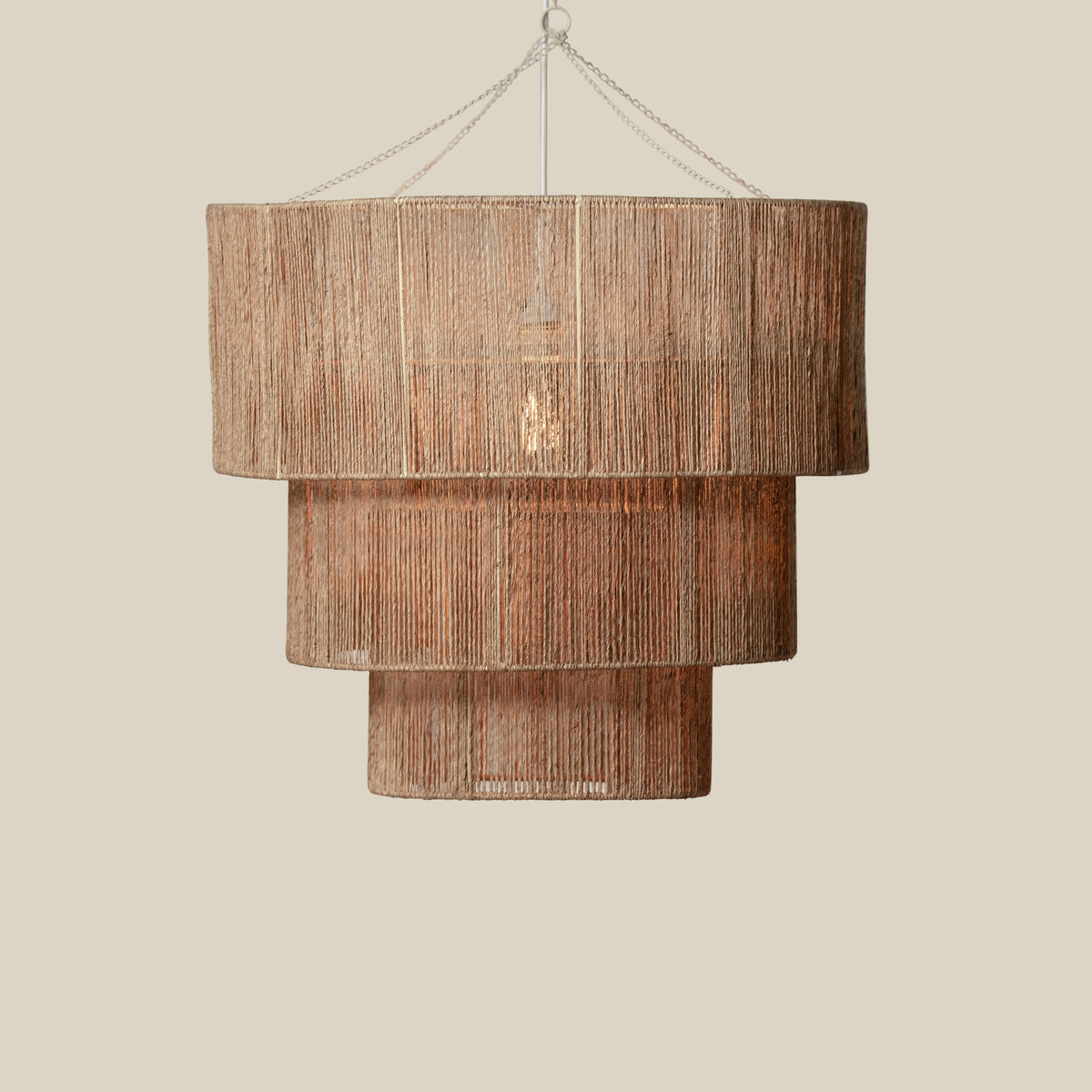 Paloma Tiered Jute Chandelier, lit in a styled room